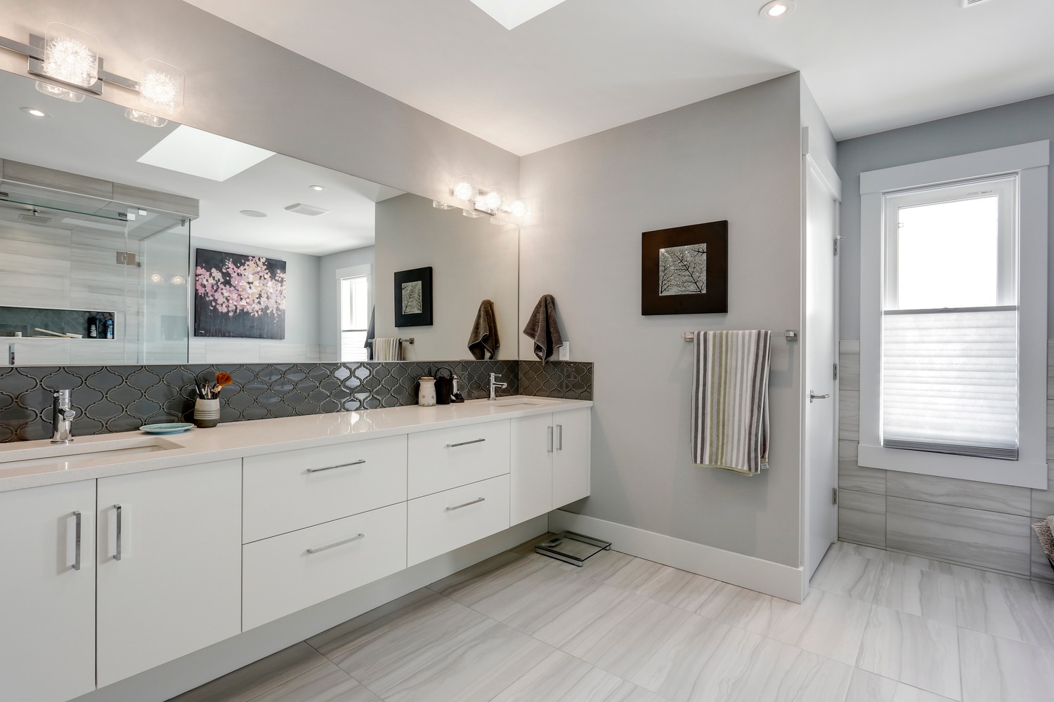 Ensuite vanity with marble-look tile and custom lighting