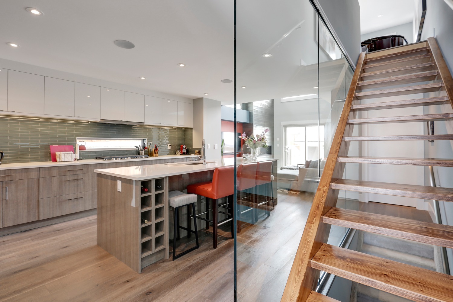 Open-tread wood staircase with glass partition beside kitchen